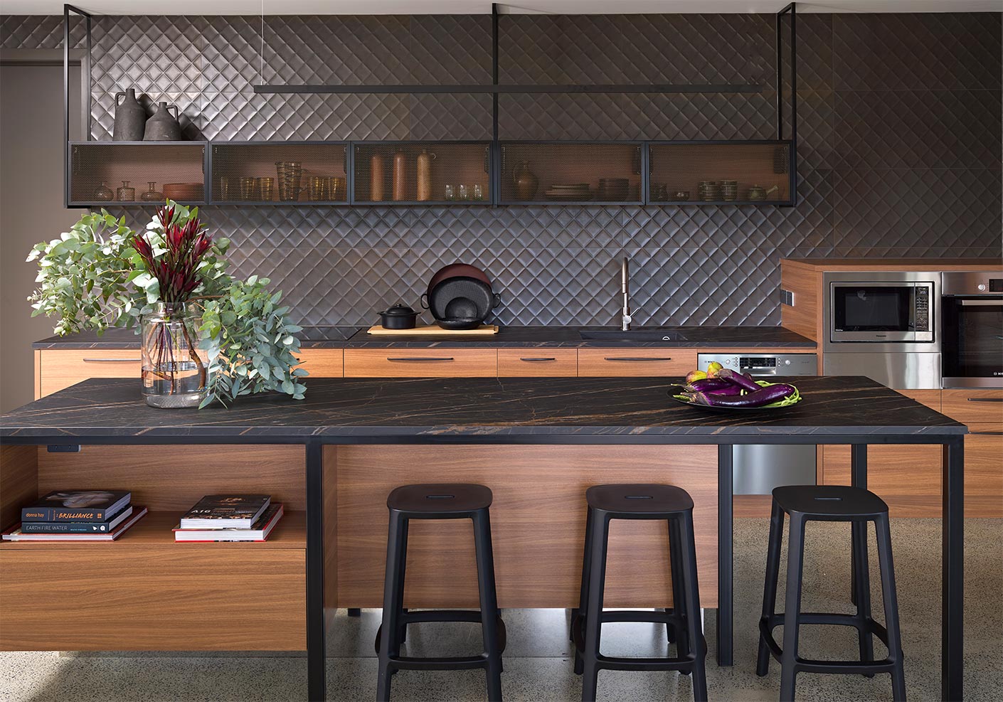 Rich mid-brown cabinetry is paired with a dark marble noir desir porcelain benchtop